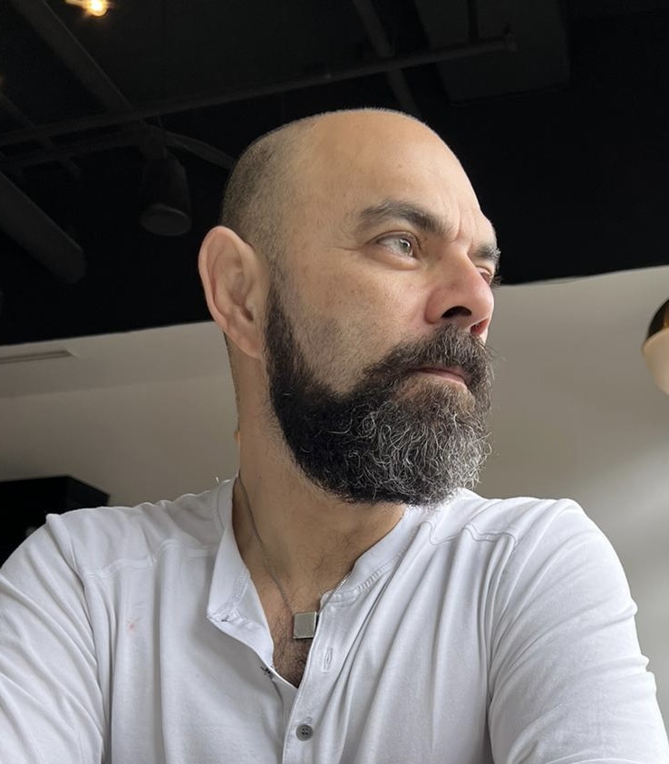Portrait of Dr. Ehsun Mirza in a white henley shirt, looking thoughtfully to the side.